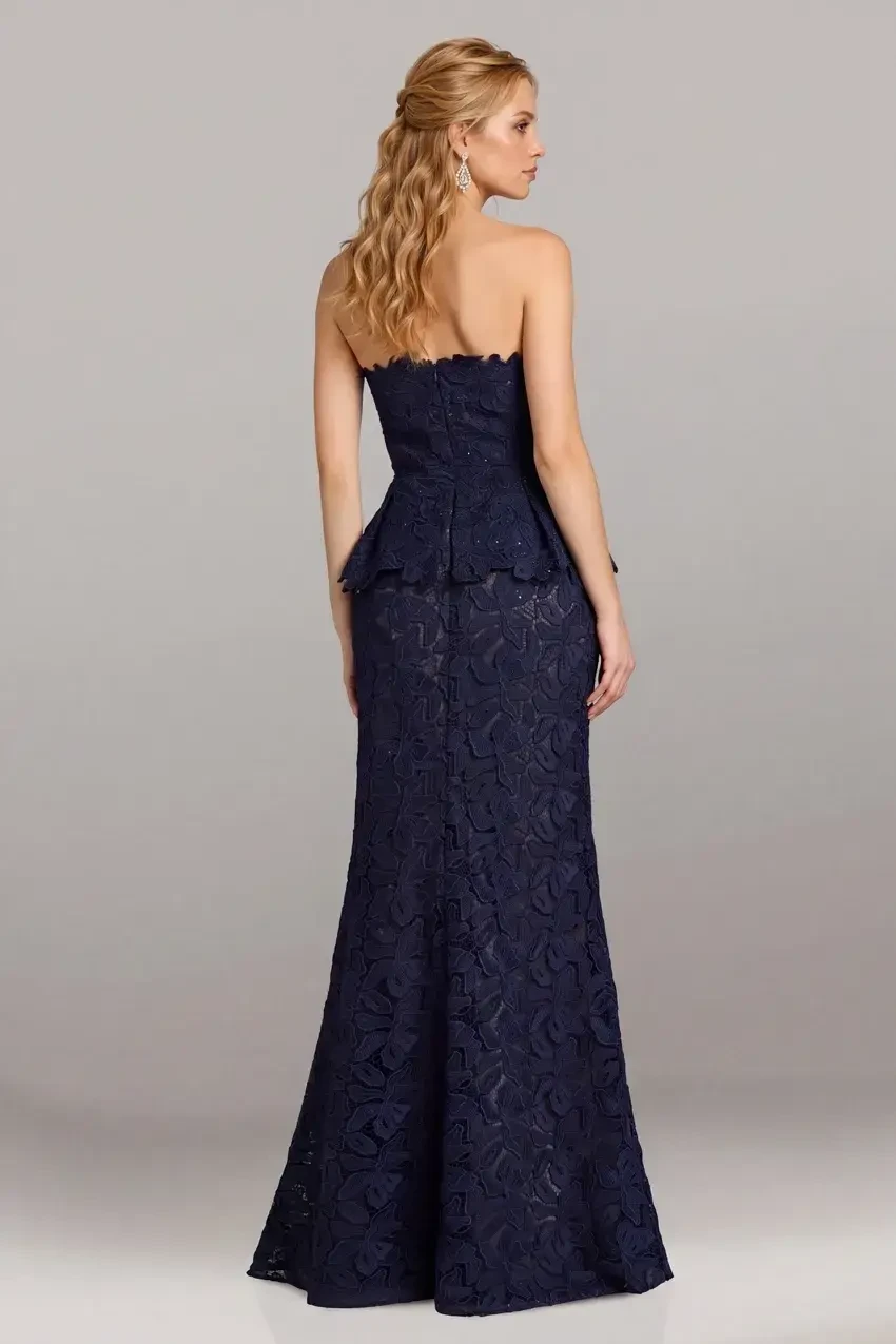 A woman wearing a strapless navy blue gown with a peplum waist and intricate lace details.