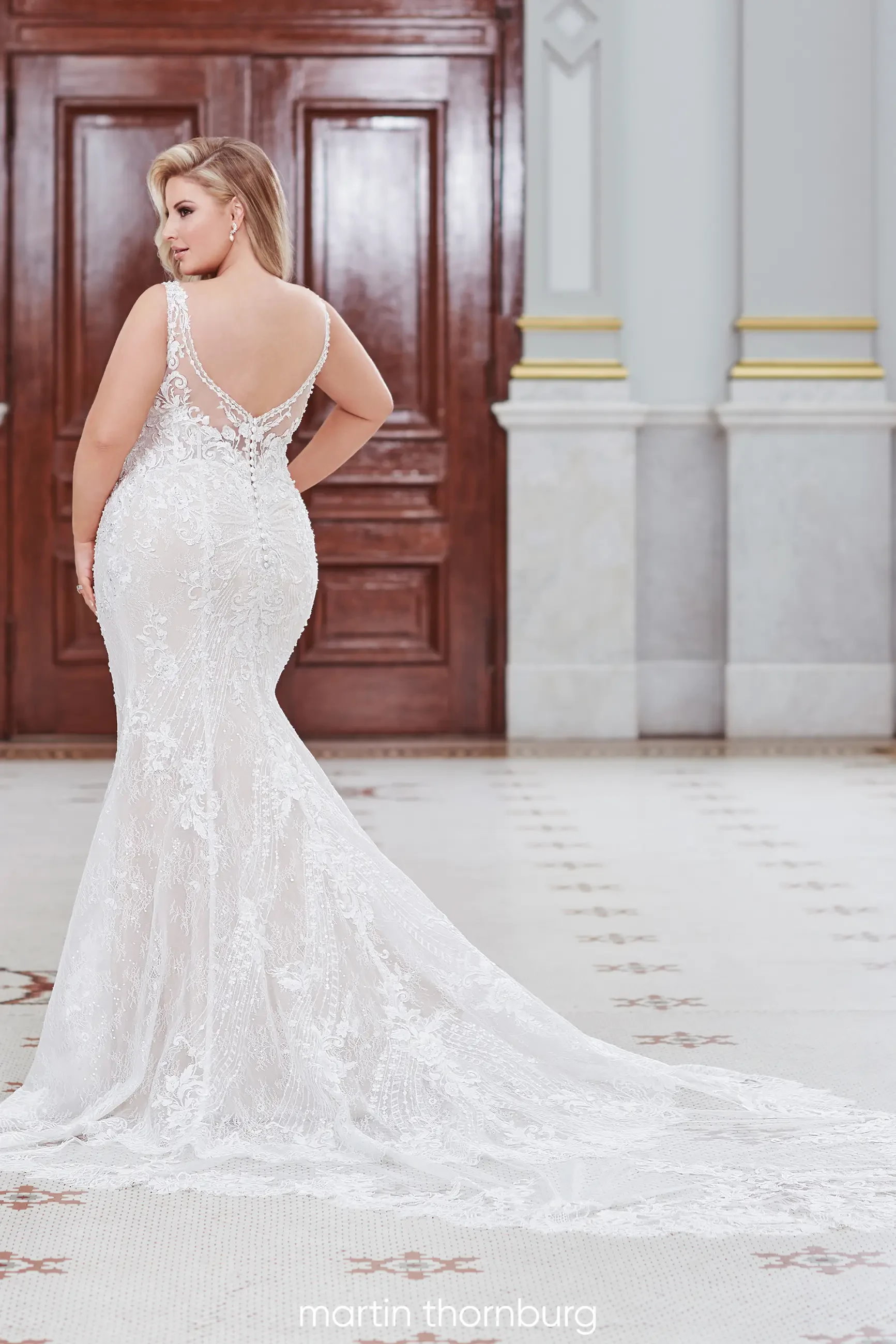 model is wearing a sleeveless plus size fit and flare bridal gown with an open low back