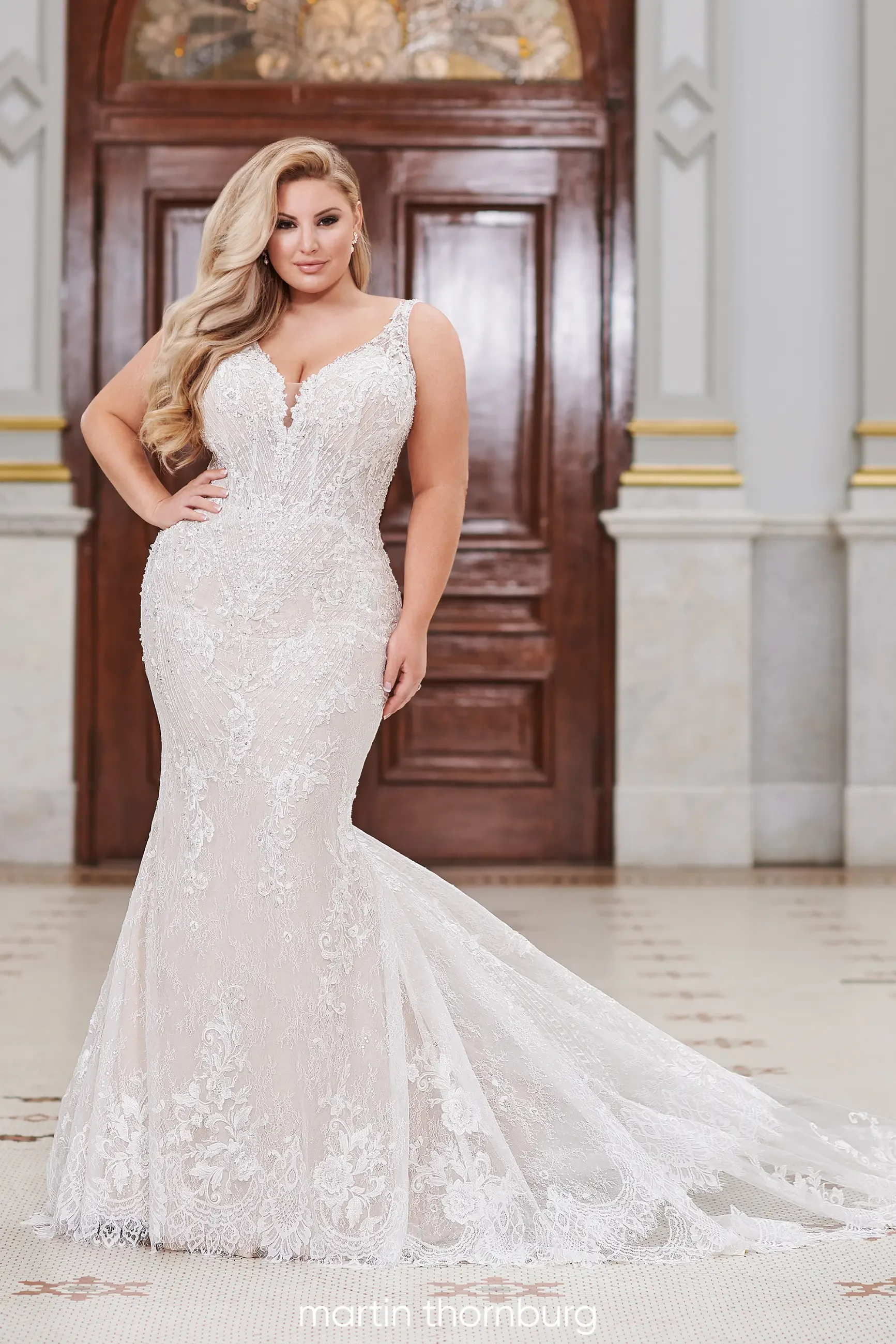 model is wearing a sleeveless plus size fit and flare bridal gown with an open low back
