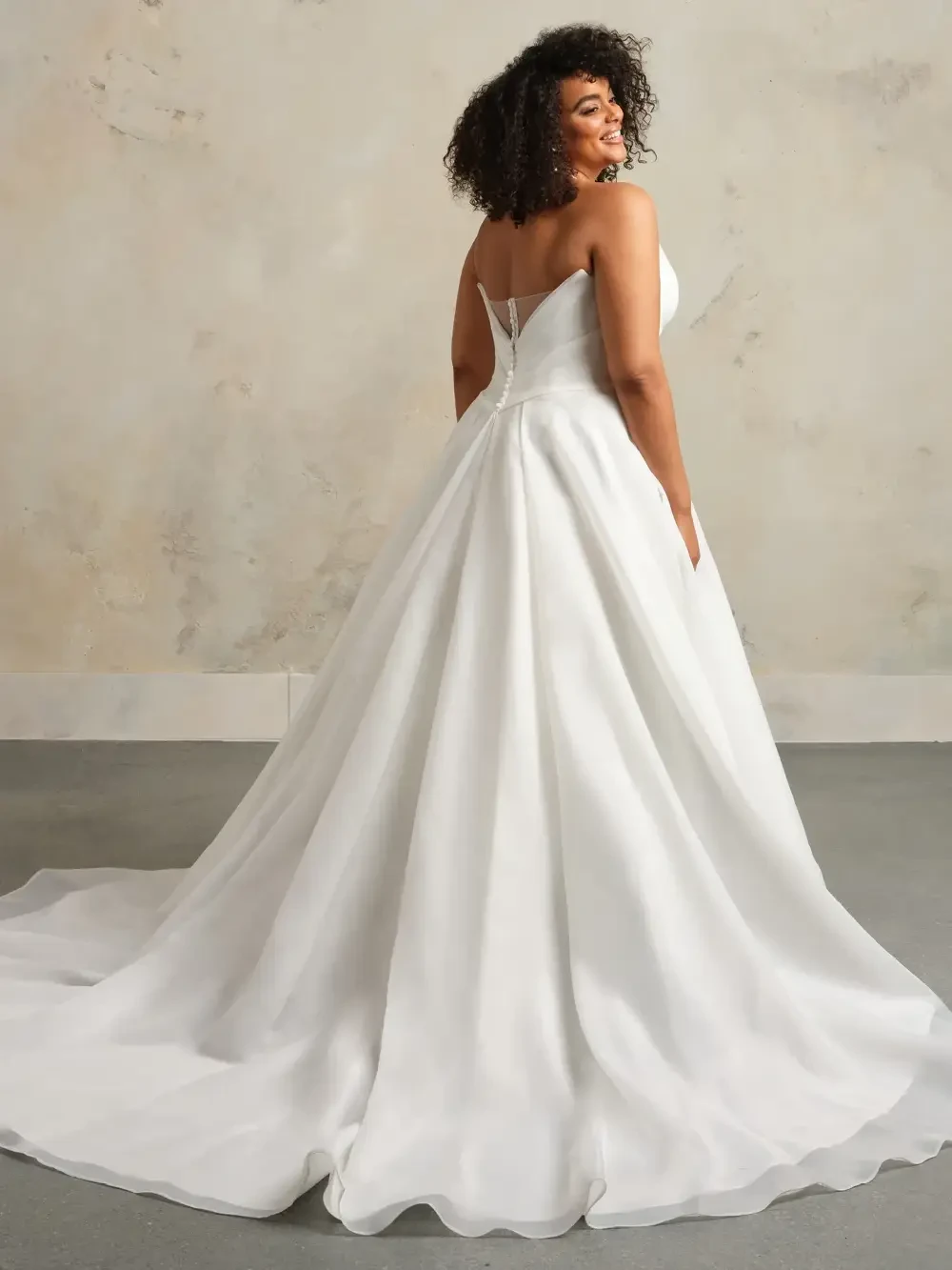 model is wearing a strapless plus size bridal gown