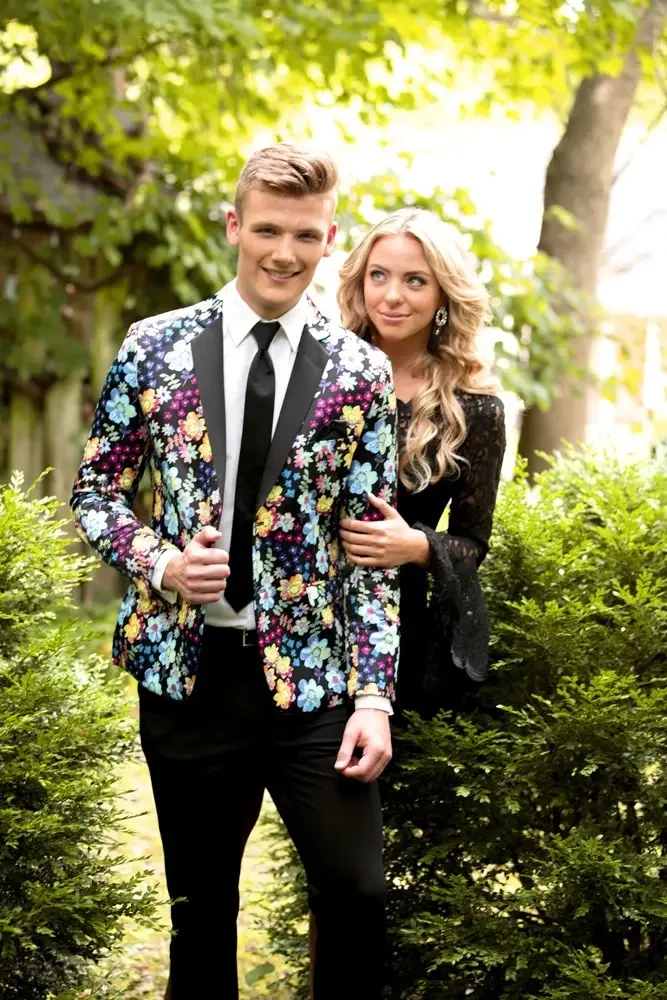 image shows a model wearing a floral suit and another model wearing a prom dress