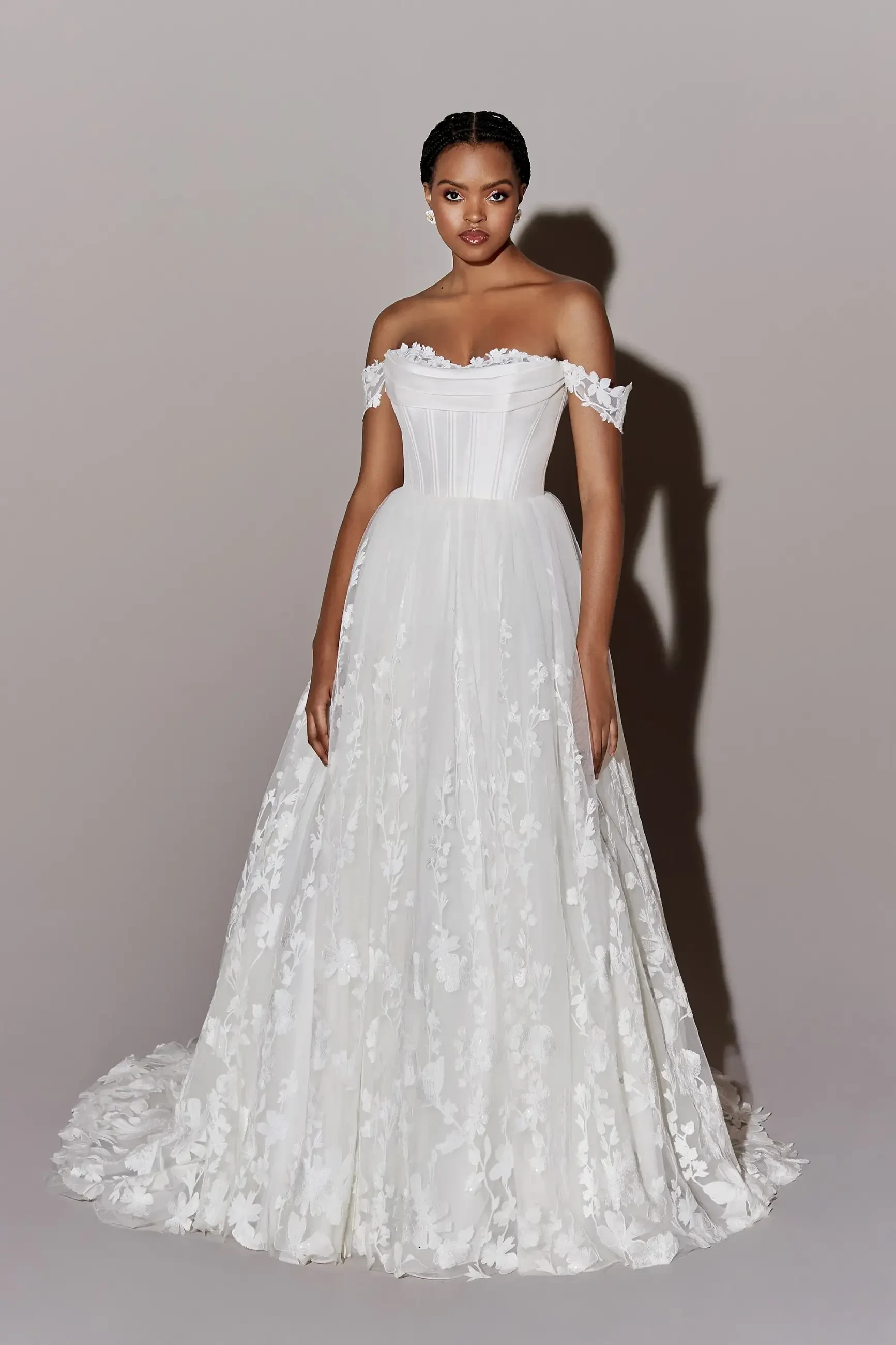 model is wearing an off the shoulder lace a-line bridal gown