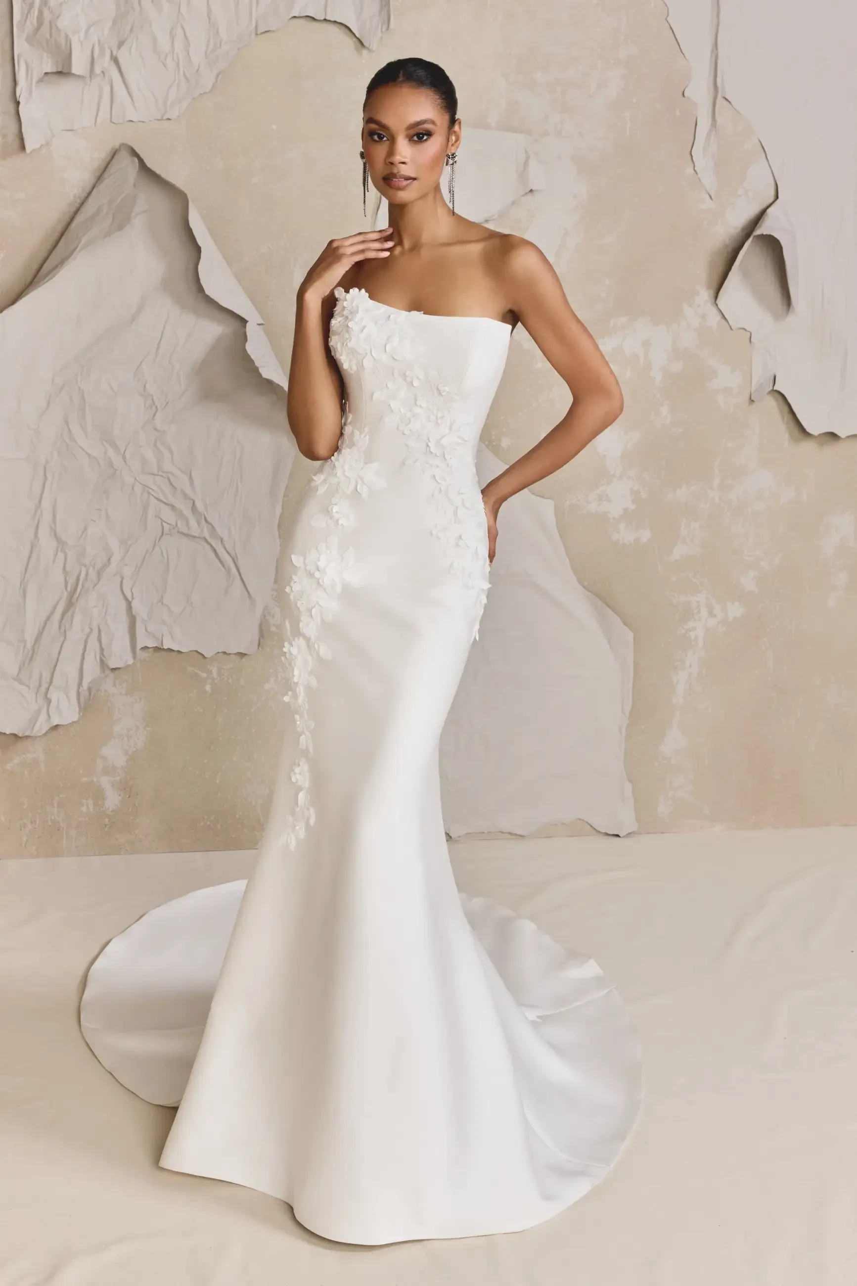 model is wearing a strapless fit and flare bridal gown with a detachable overskirt