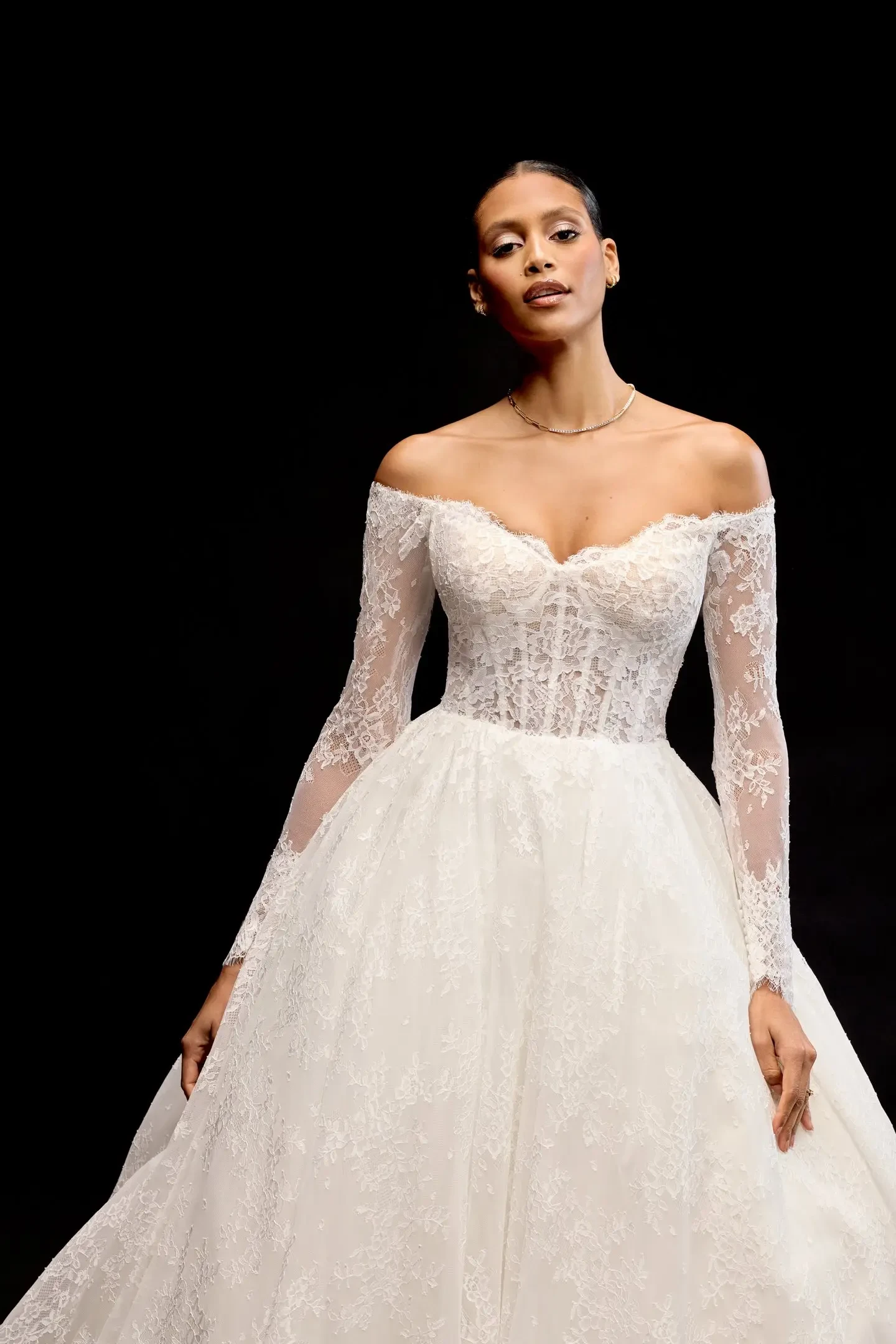 Model is wearing an off the shoulder long sleeve a-line lace wedding dress