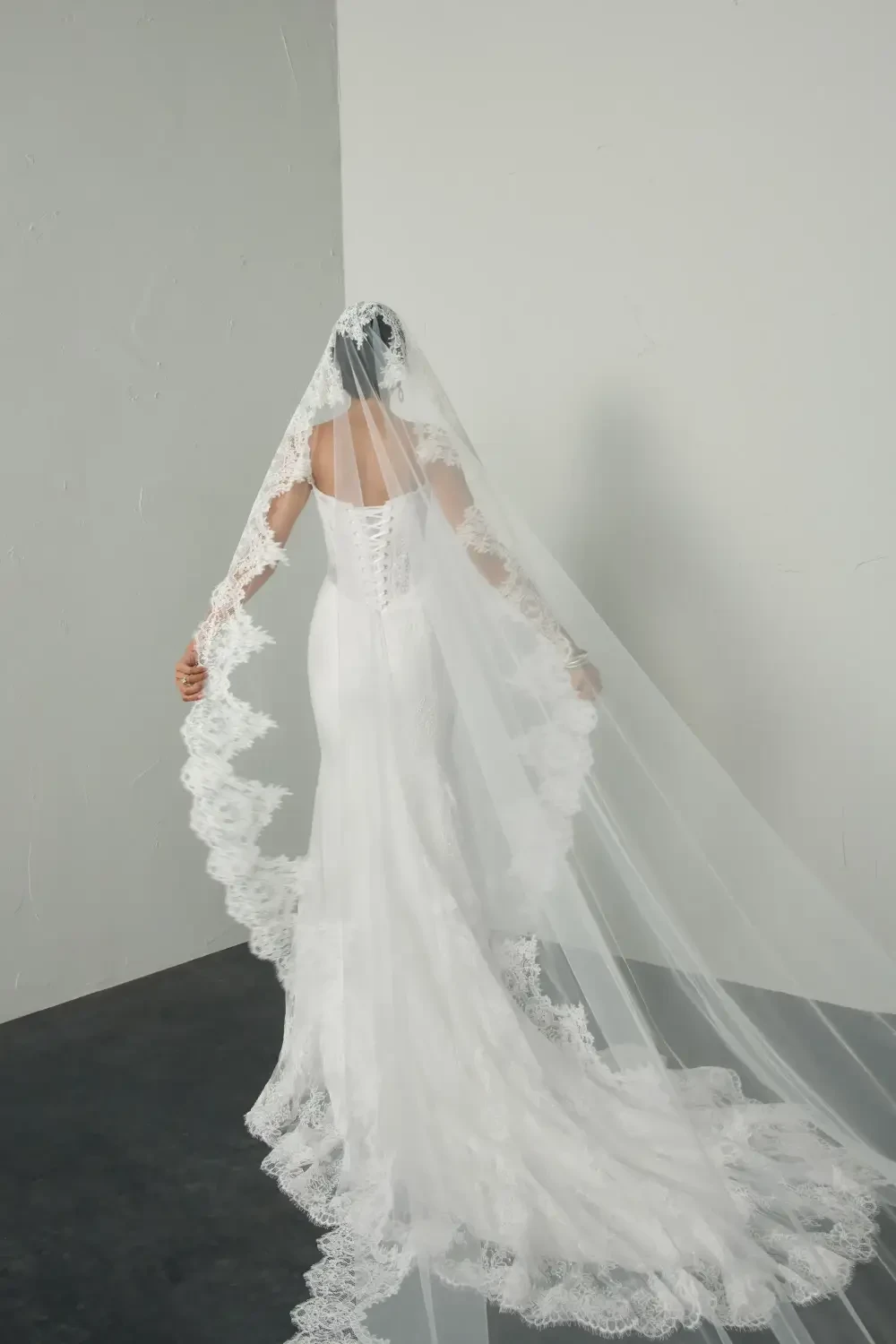 model is wearing a lace bridal gown with a dramatic lace veil
