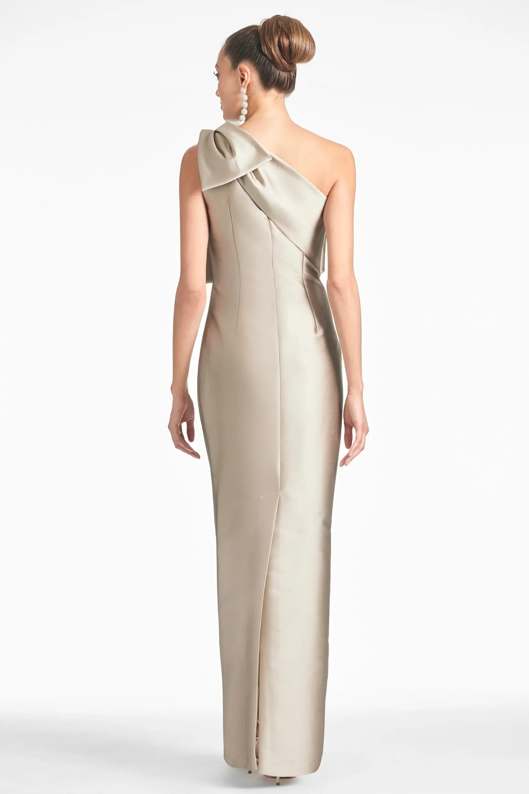 Model is wearing a floor length asymmetrical one shoulder mikado gown with a large bow