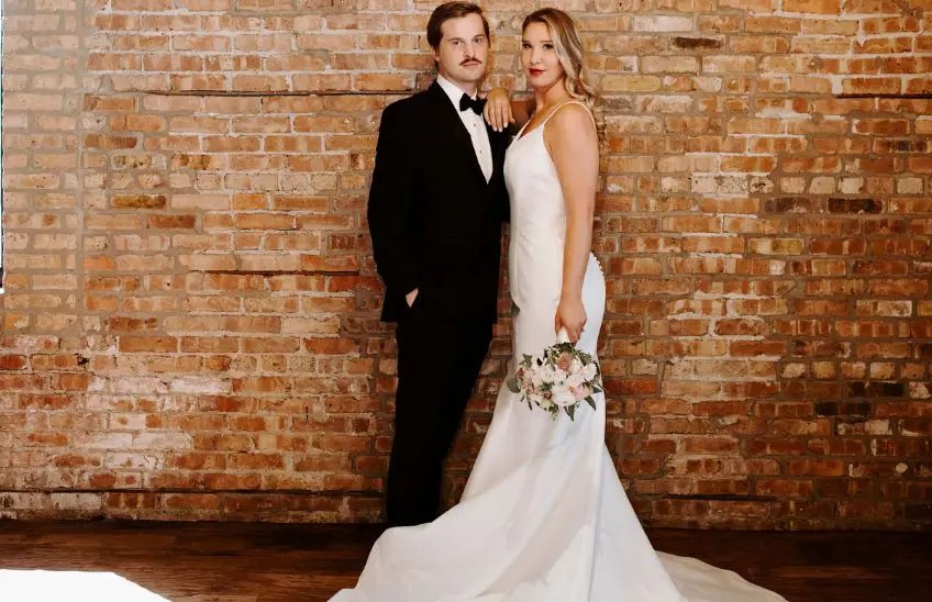 Groom in a black tuxedo next to a bride in a white wedding gown