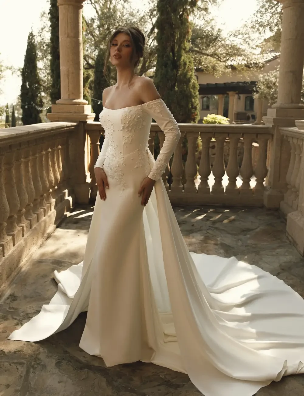 model is wearing an off the shoulder sheath wedding dress