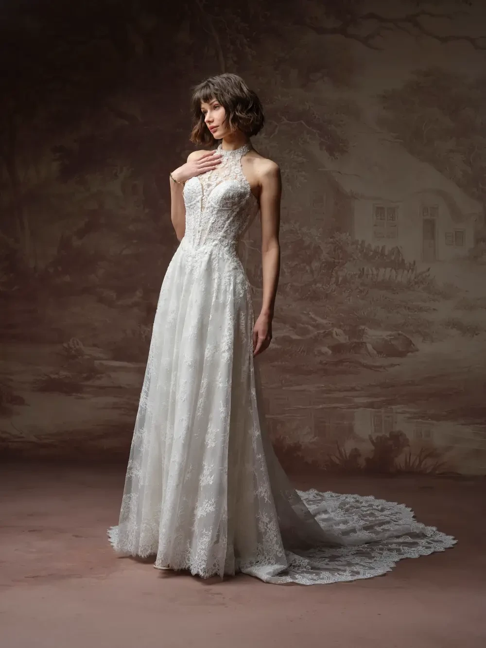 A model wearing an elegant, sleeveless white wedding dress with intricate lace detailing, posed against a classical, painted backdrop.