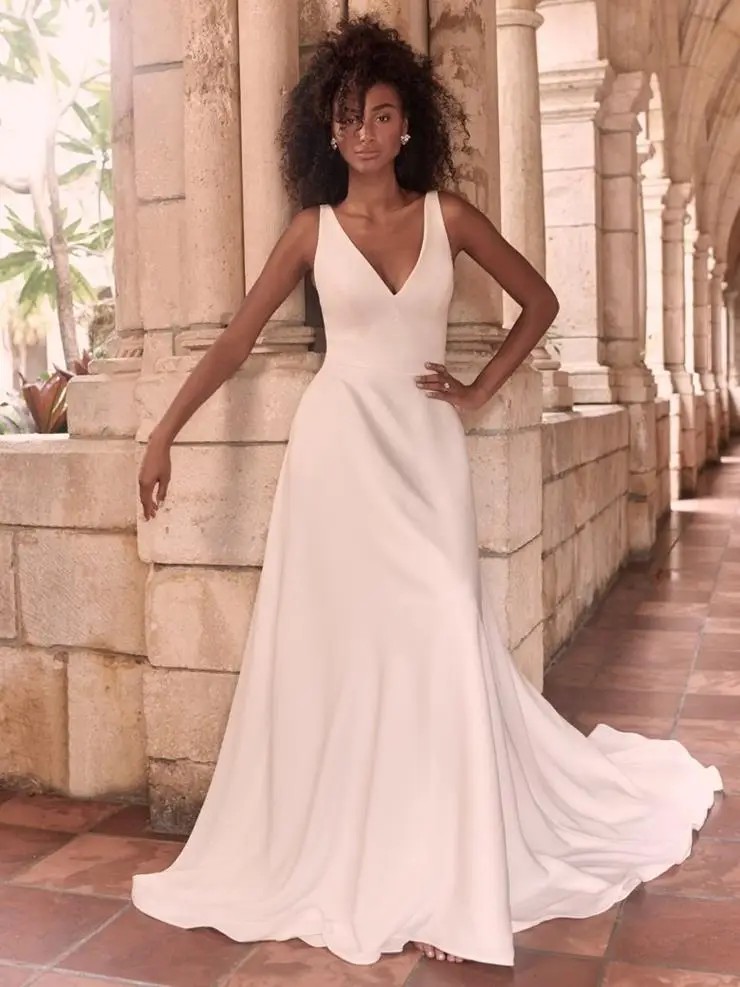 Model is wearing a sleeveless a-line wedding gown with a v-neckline by maggie sottero