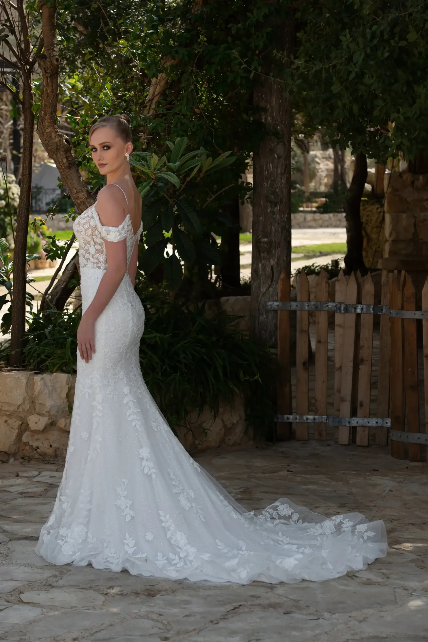 Model is wearing an off the shoulder fit and flare wedding dress by elissar