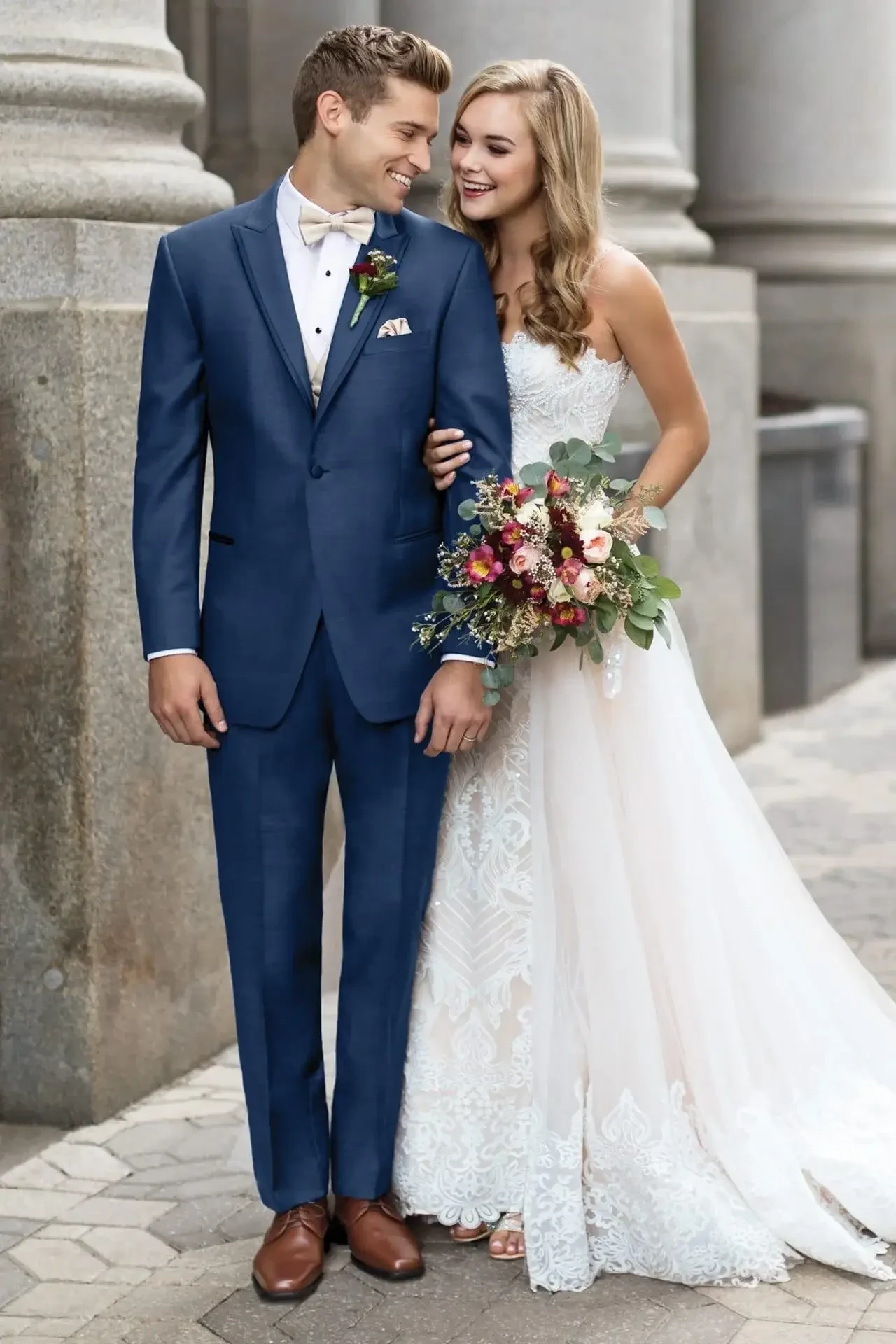 image shows a male model wearing a navy blue tux and a female model wearing a wedding dress